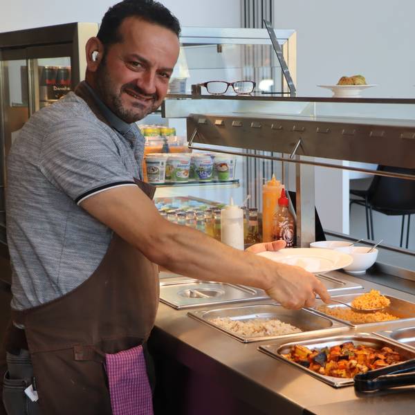 Das Bild zeigt Küchenchef Mesrur Alev beim Befüllen der Teller.
