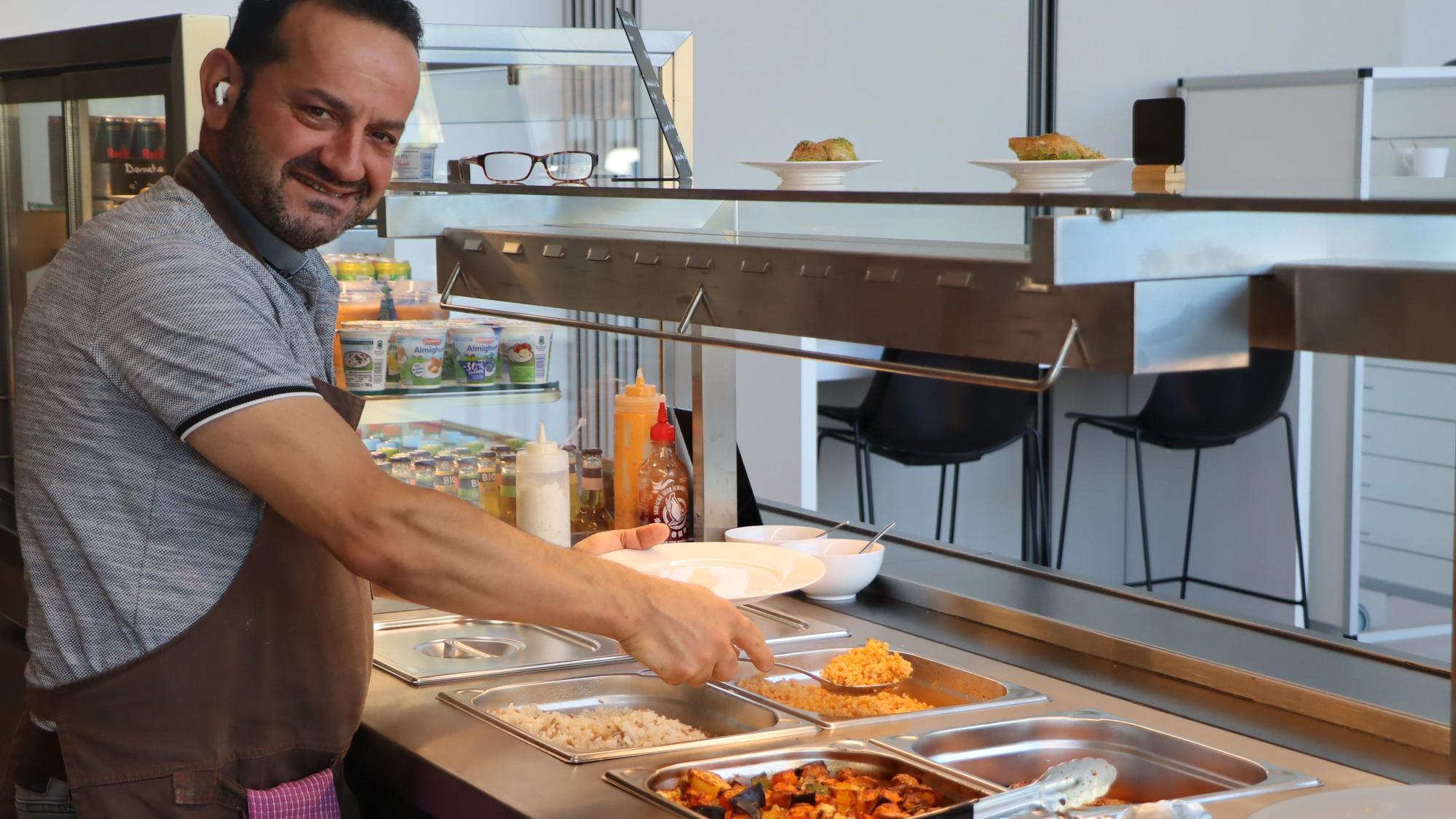 Das Bild zeigt Küchenchef Mesrur Alev beim Befüllen der Teller.