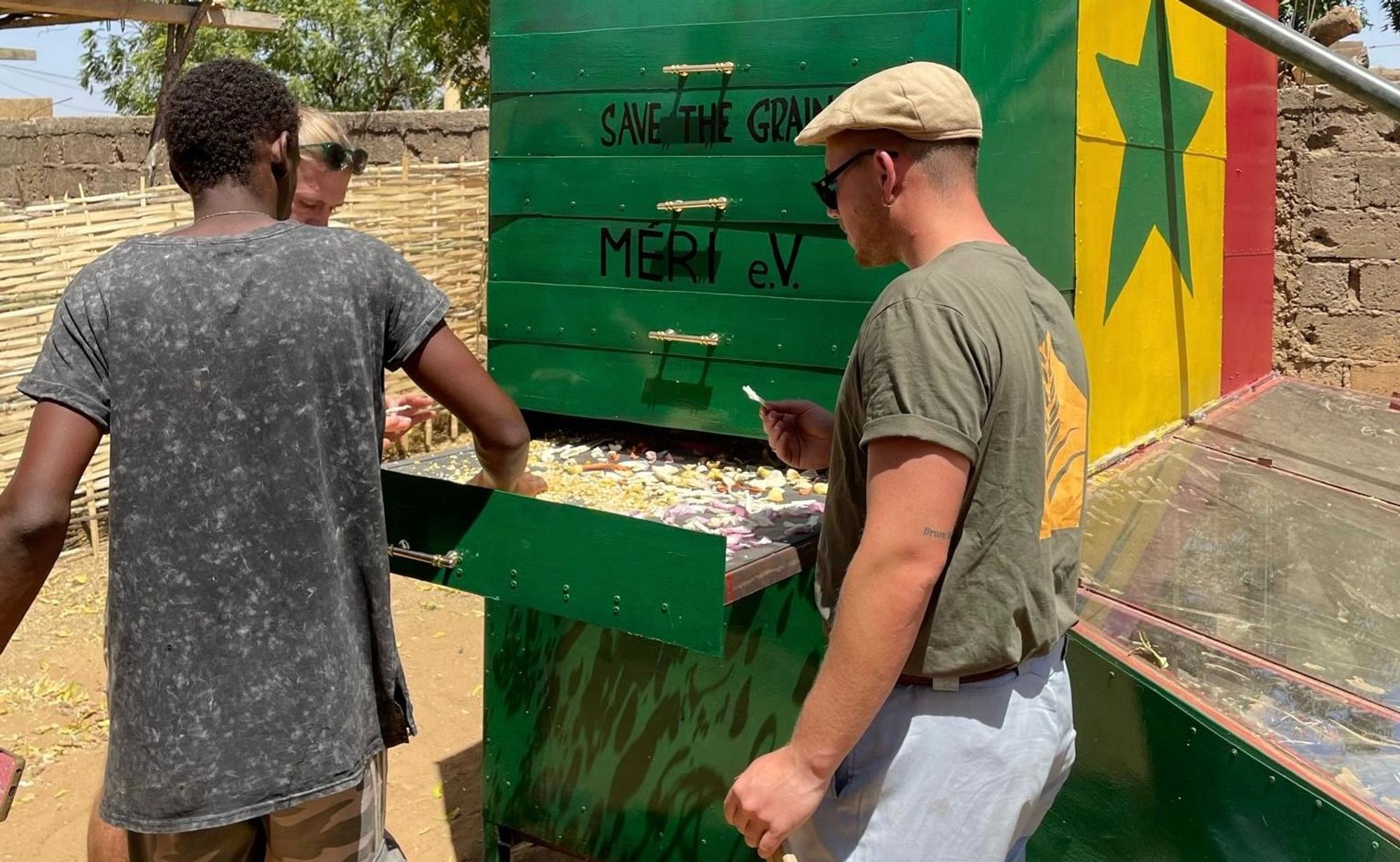 Drei Menschen trocknen Nahrungsmittel im Solartrockner im Senegal.