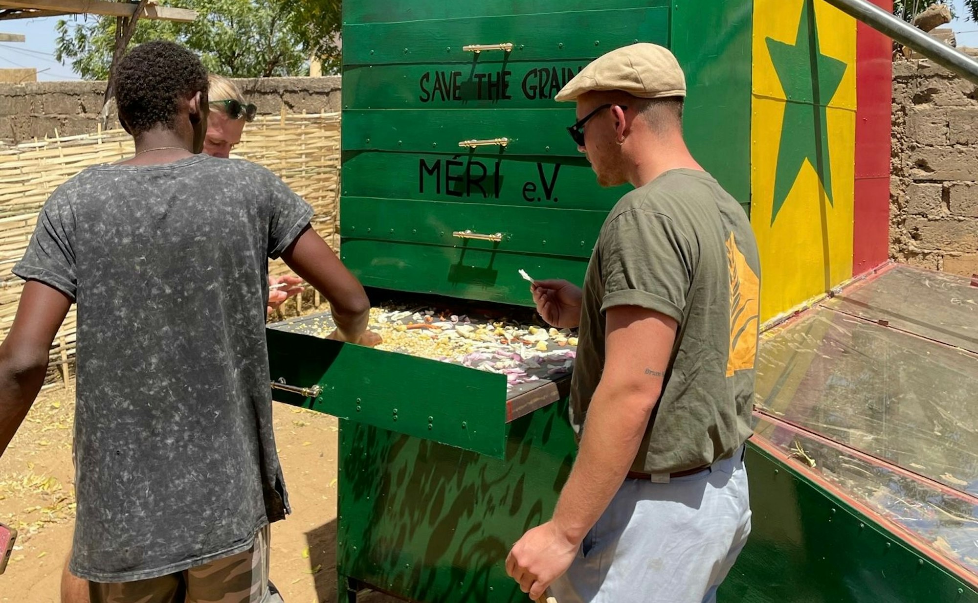 Drei Menschen trocknen Nahrungsmittel im Solartrockner im Senegal.