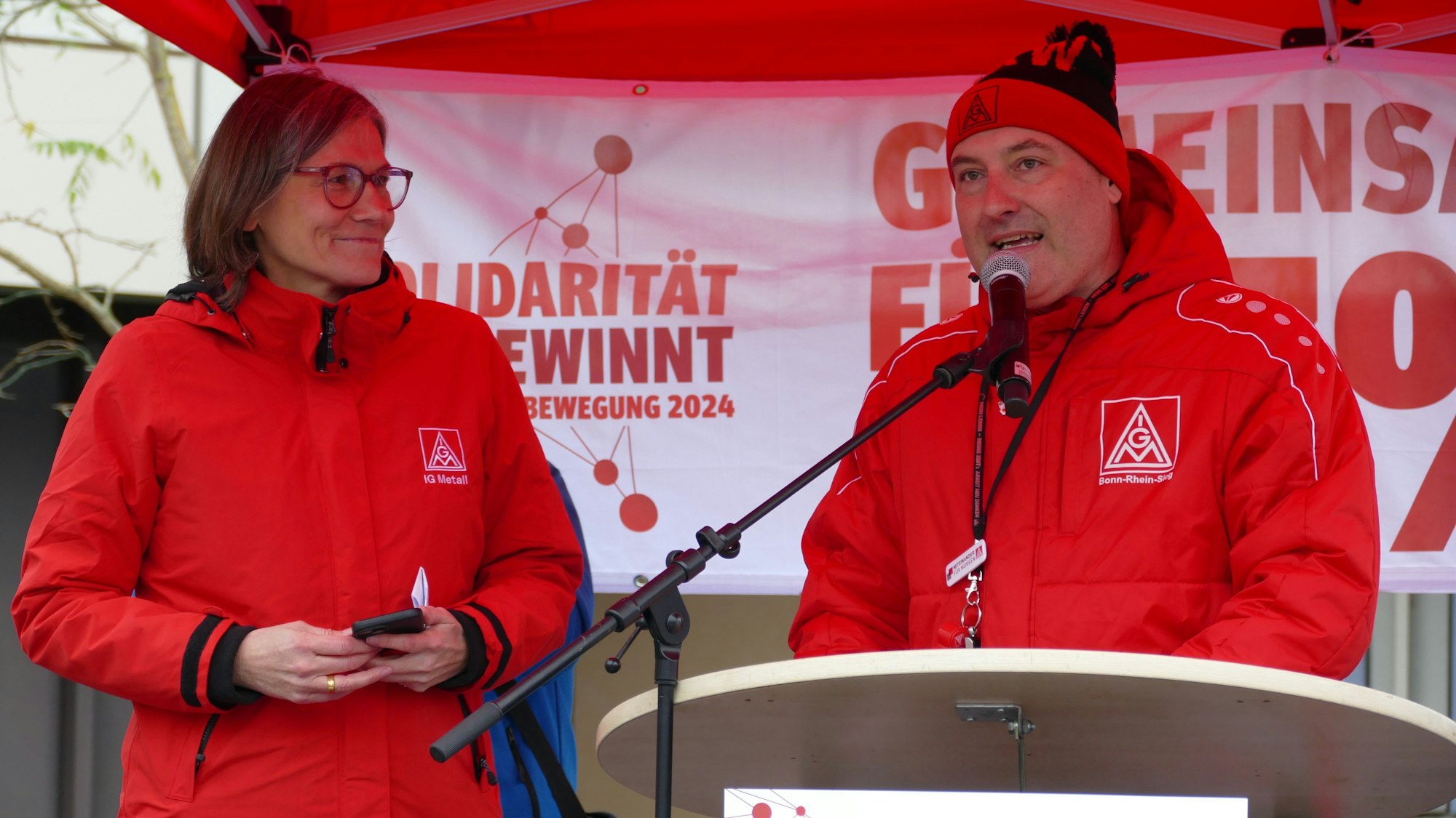 Eine Frau und ein Mann vor einem Mikrofon.