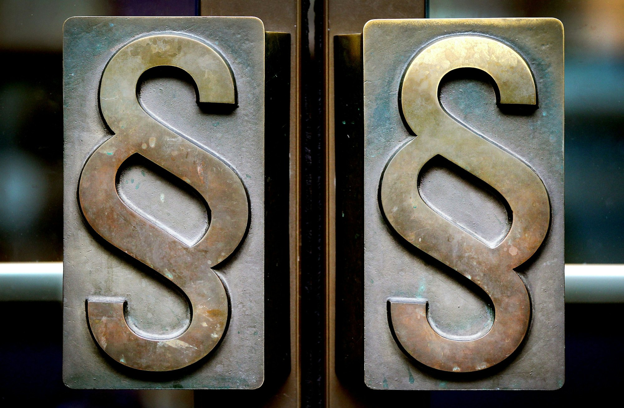 Paragrafen-Symbole sind an Türgriffen am Eingang zum Landgericht Bonn angebracht.