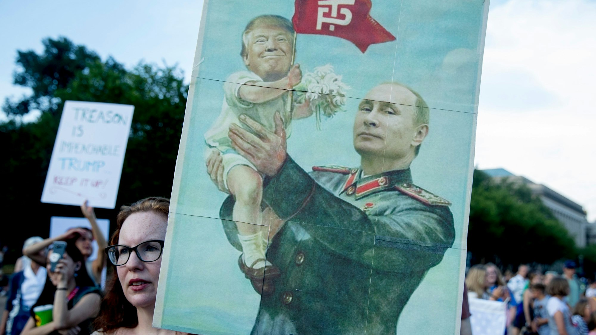 Eine Frau hält während eines Protests gegen das Treffen von Trump und Putin im Jahr 2018 vor dem Weißen Haus ein Schild, auf dem die beiden Präsidenten karikiert sind.