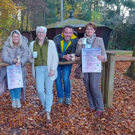 Eine Gruppe von sieben Menschn steht vor einer Grillhütte im Herbstwald.