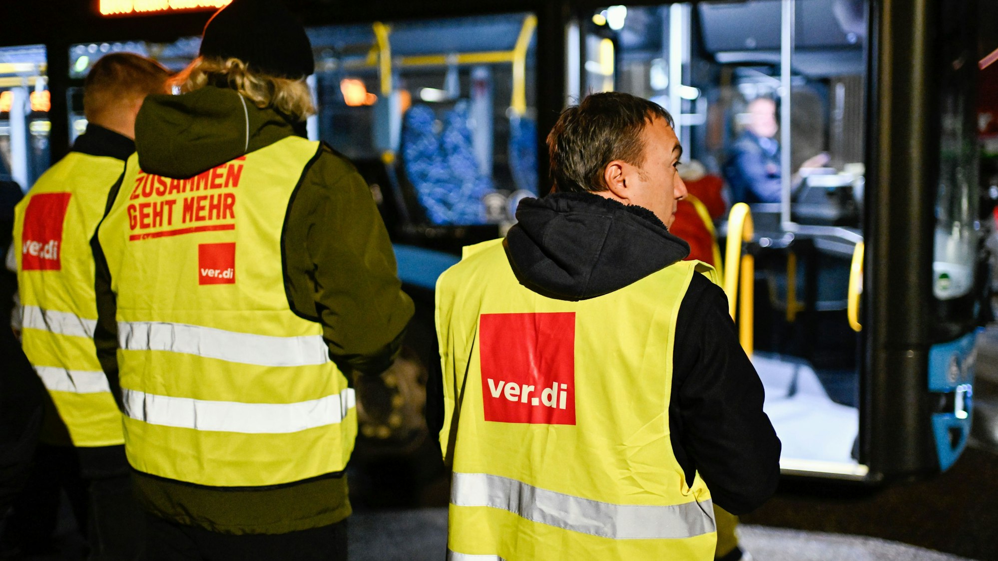 Menschen in verdi-Westen. Im Hintergrund eine Bahn.