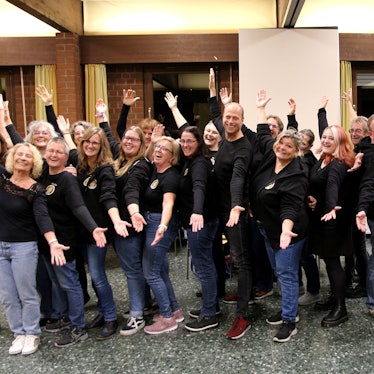 Das Foto zeugt die Chormitglieder mit ausladender Geste.