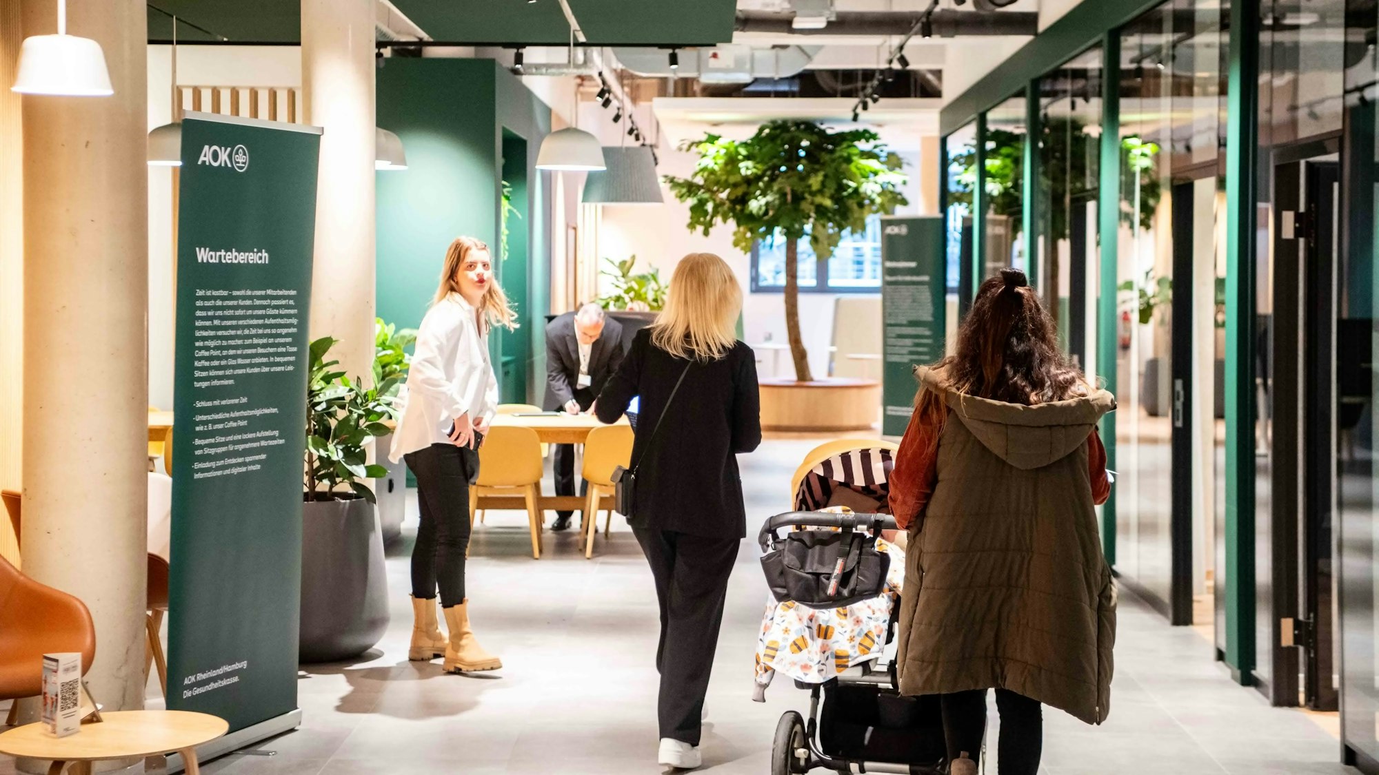 Das Bild zeigt den Eingangsbereich der AOK in Euskirchen. Eine Kundin folgt einer Mitarbeiterin in einen Besprechungsraum.