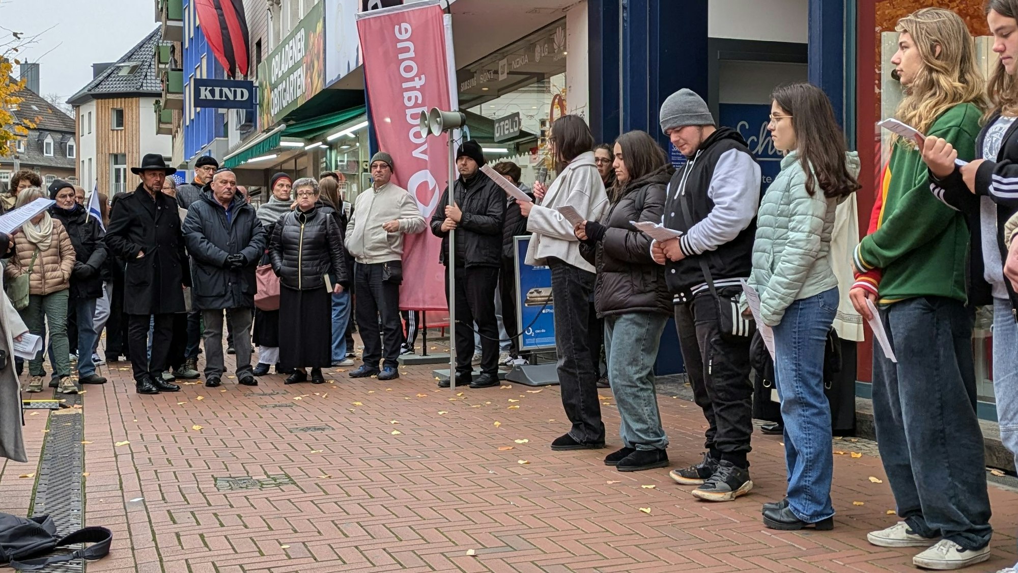 Schüler lesen auf einem Platz Texte vor, während andere zuhören.