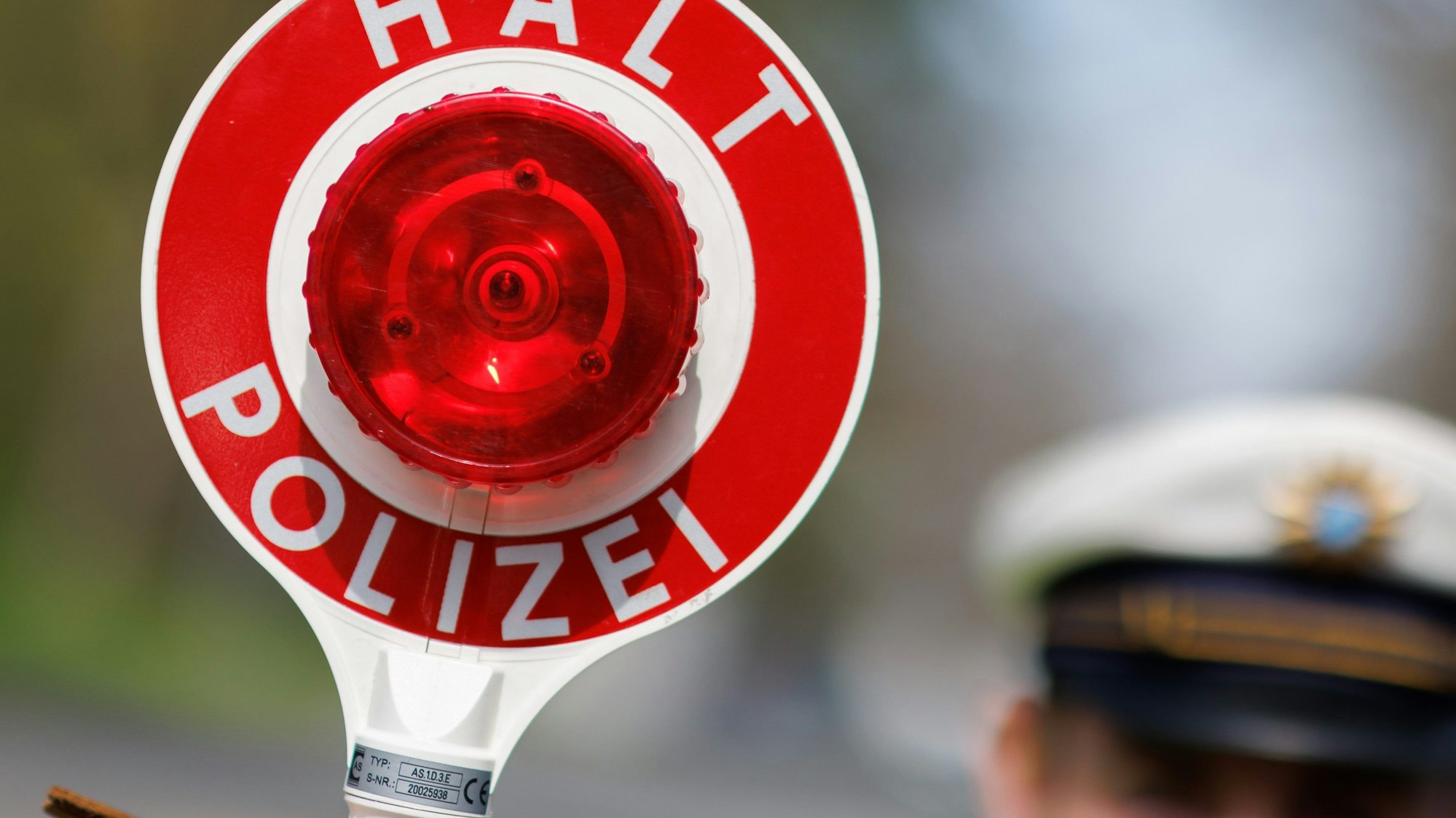 Ein Polizist zieht ein Fahrzeug mit seiner Kelle aus dem Verkehr.