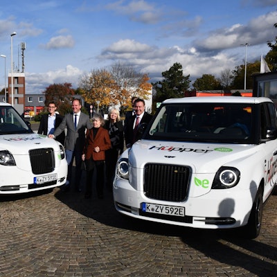 Das Foto zeigt zwei Großraumlimousinen mit Vertretern der Stadt bei der Einführung des Hüpper.