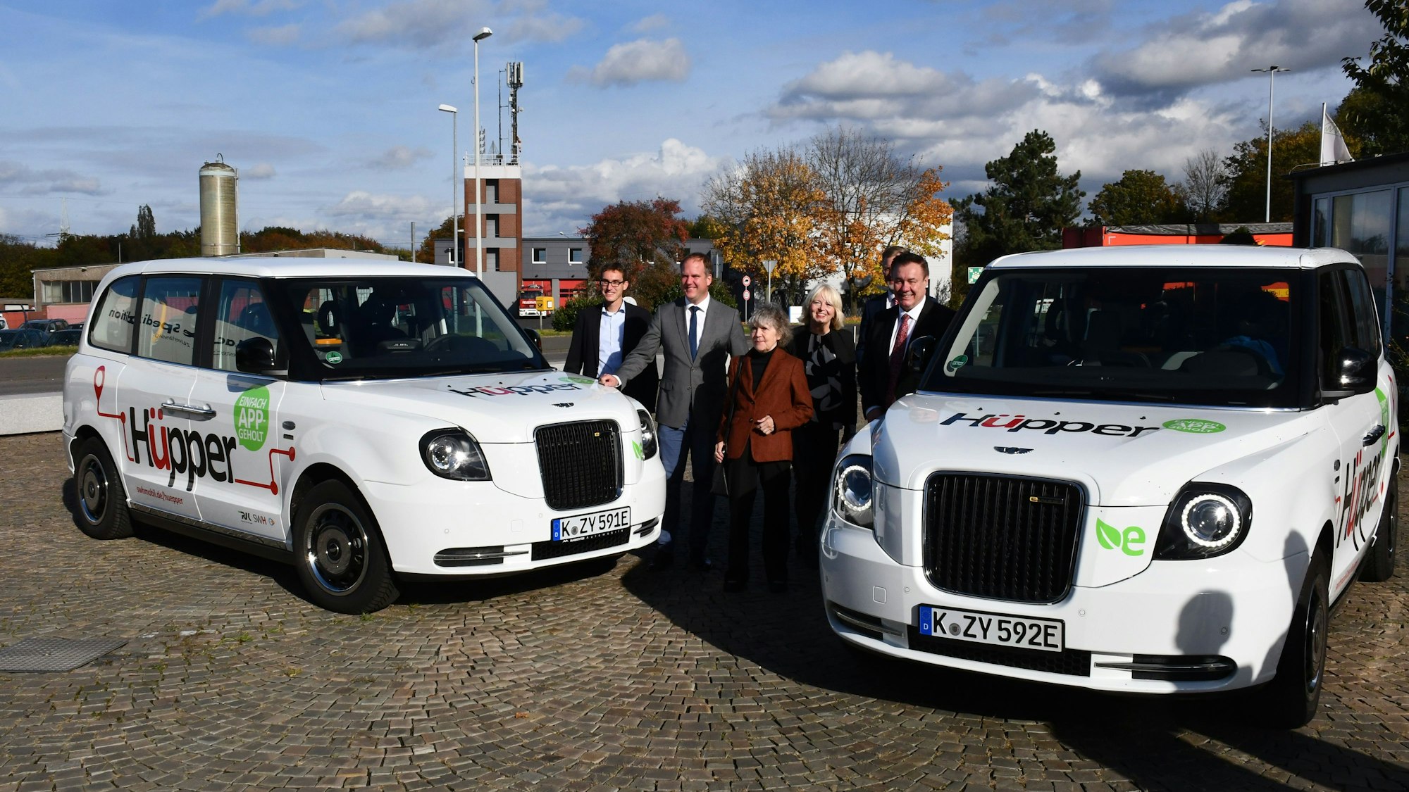 Das Foto zeigt zwei Großraumlimousinen mit Vertretern der Stadt bei der Einführung des Hüpper.