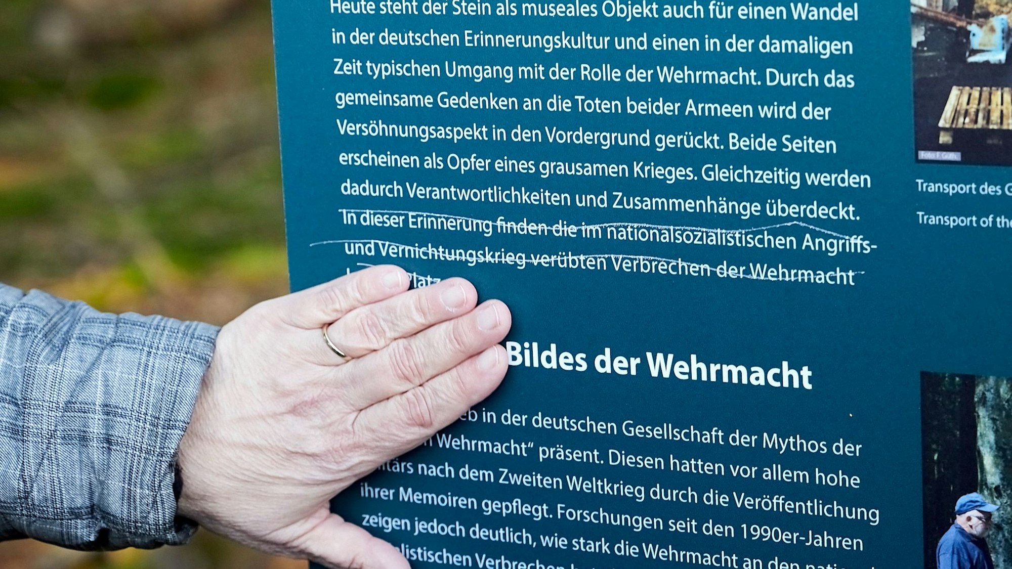 Eine Hand zeigt auf eine Stelle an einer Gedenktafel. Dort wurde der Satz: „In dieser Erinnerung finden die im nationalsozialistischen Angriffs- und Vernichtungskrieg verübten Verbrechen der Wehrmacht ihren Platz“ durchgestrichen.