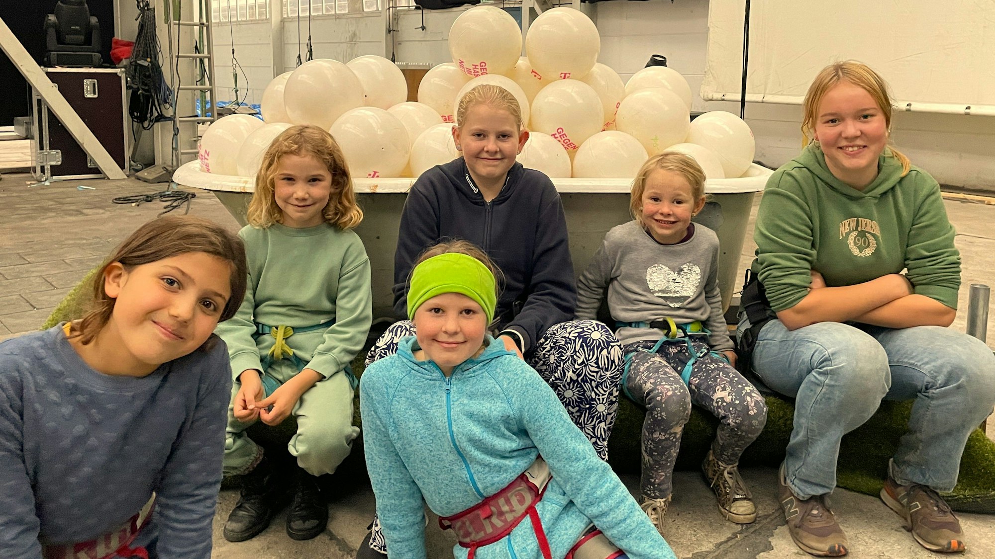 Sechs Mädchen zwischen sechs und 16 Jahren sind Ensemble-Mitglieder des Flugtheaters, sie sitzen vor einer Wanne mit weißen Luftballons.