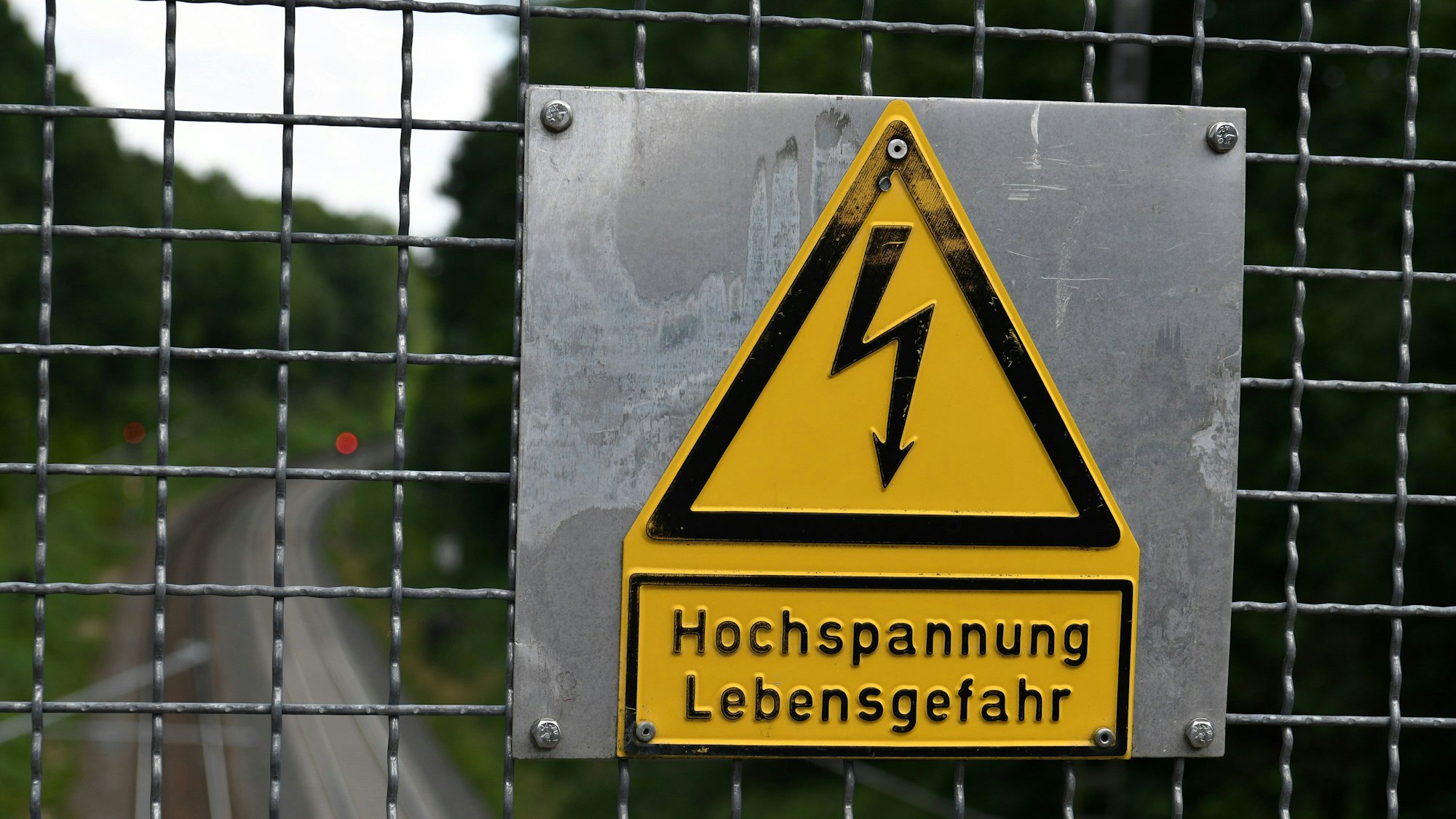 Warnschild Hochspannung Lebensgefahr an einer Brücke über eine elektrifizierte Bahnstrecke.