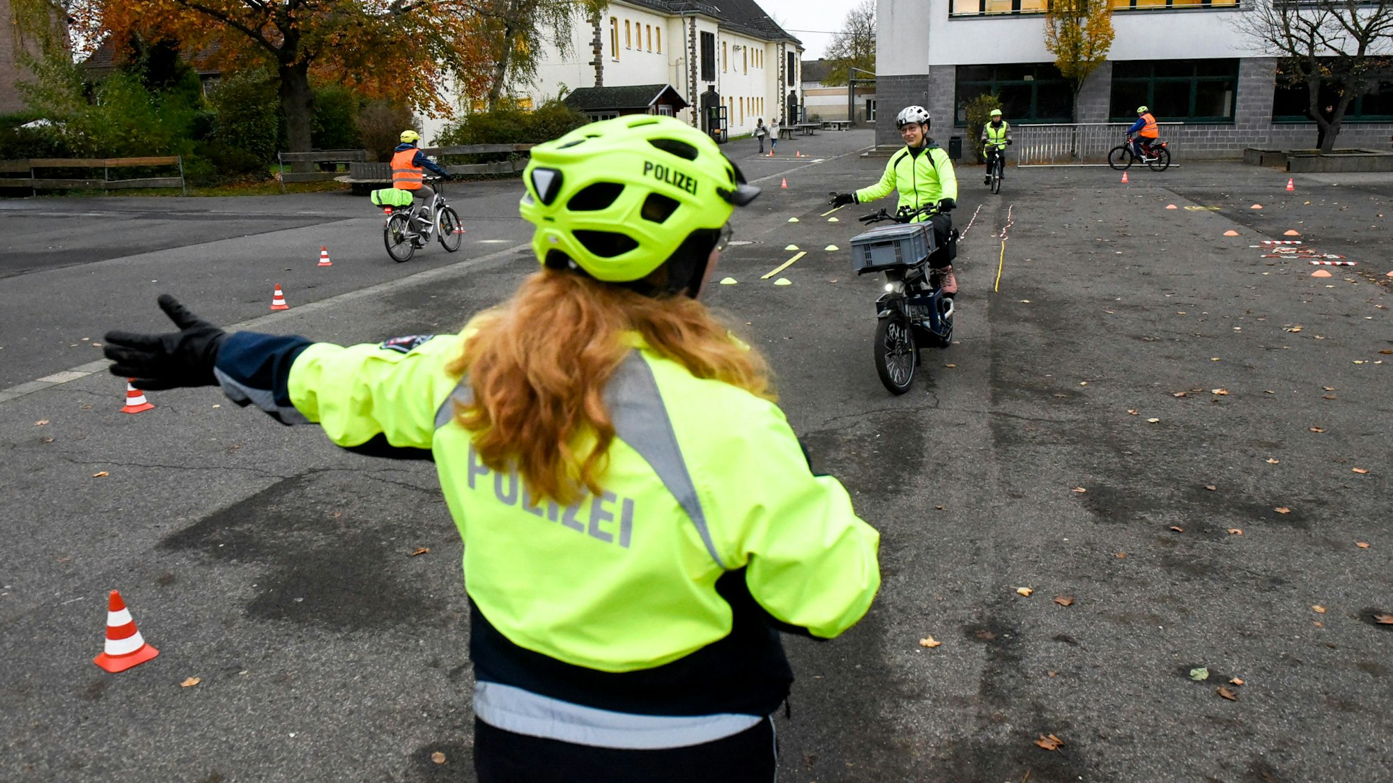 Das Foto zeigt eine Polizistin, die Radfahrern Anweisungen in einem Parcours gibt.