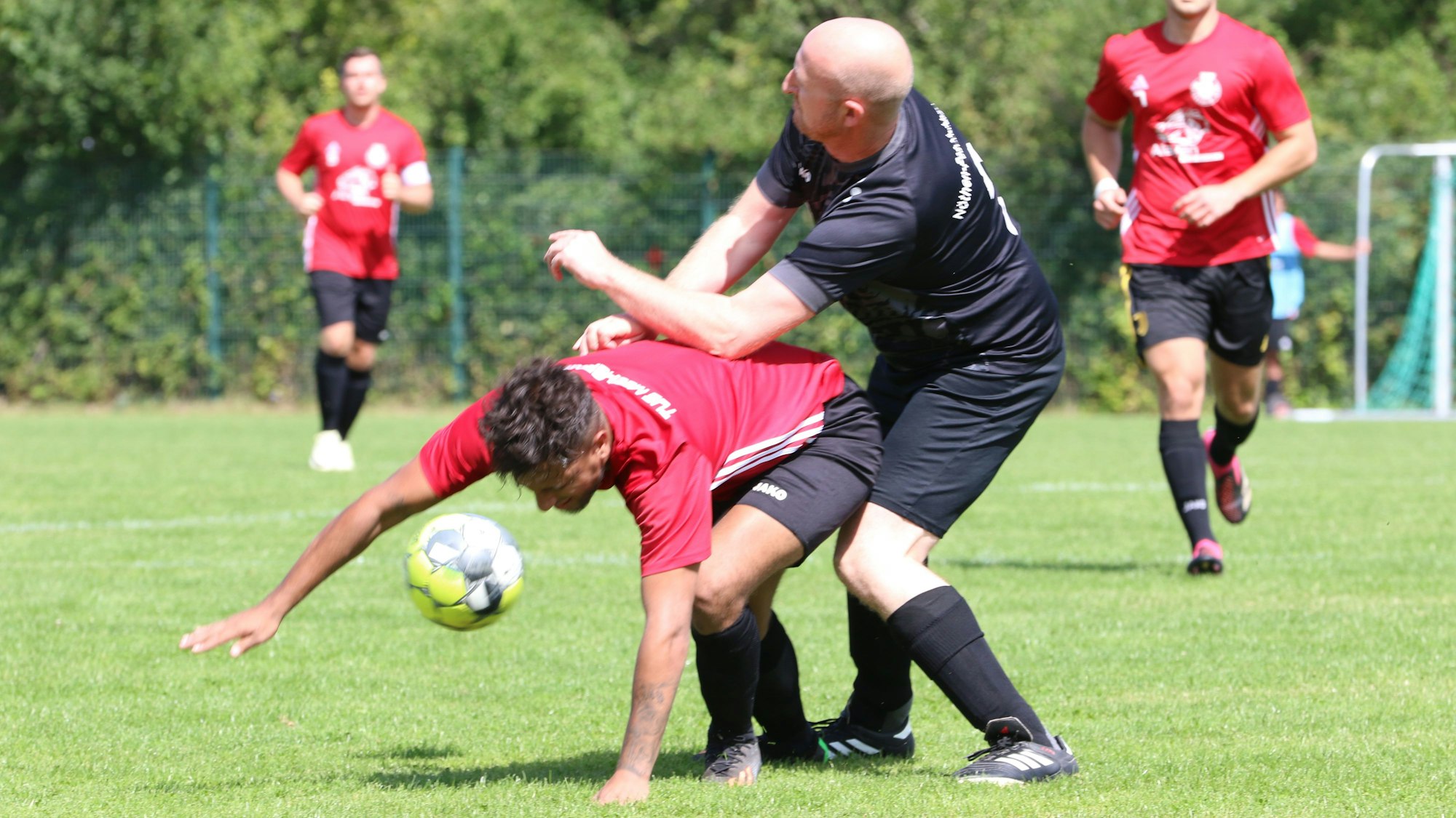 Schleidens Bürgermeister Ingo Pfennings als Fußballer im Zweikampf mit dem Mechernicher Adrian Meyer. Meyer stützt sich mit einer Hand auf dem Rasen ab.
