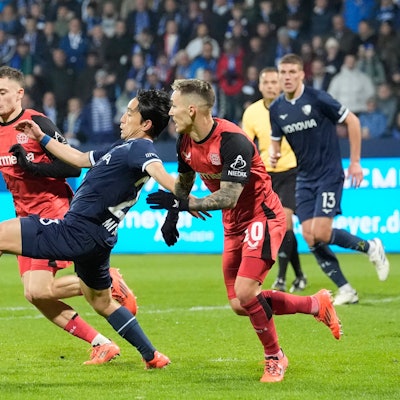 Bochums Koji Miyoshi mit den Leverkusenern Florian Wirtz und Alejandro Grimaldo.