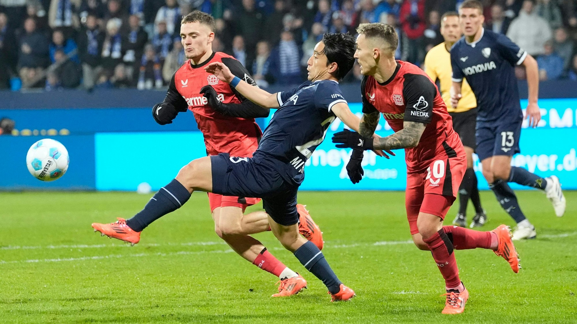 Bochums Koji Miyoshi mit den Leverkusenern Florian Wirtz und Alejandro Grimaldo.