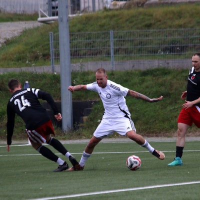 Ein Fußballspieler wird im Strafraum von einem Gegner am Fußb getroffen.