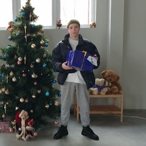 Zwei Jugendliche halten Wichtelpäckchen in ihren Armen. Sie stehen neben einem Weihnachtsbaum.