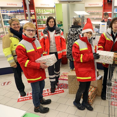 Jugendrotkreuzler und Mitarbeiterinnen von DRK und Feuerwehr holen gespendete Pakete für die Wichtelaktion 2022 in einer Apotheke ab.