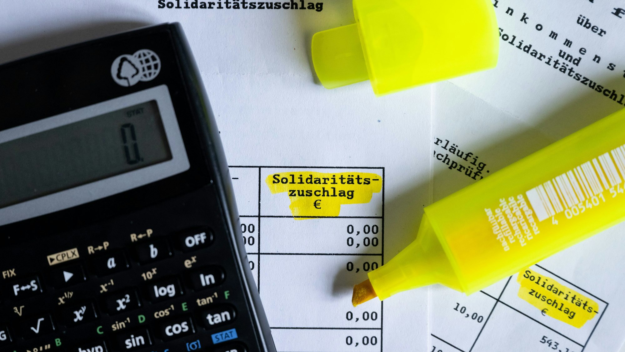 ILLUSTRATION - 23.01.2023, Bayern, München: Das Wort ·Solidaritätszuschlag· ist neben einem Taschenrechner und einem Textmarker auf einem Steuerbescheid zu sehen.