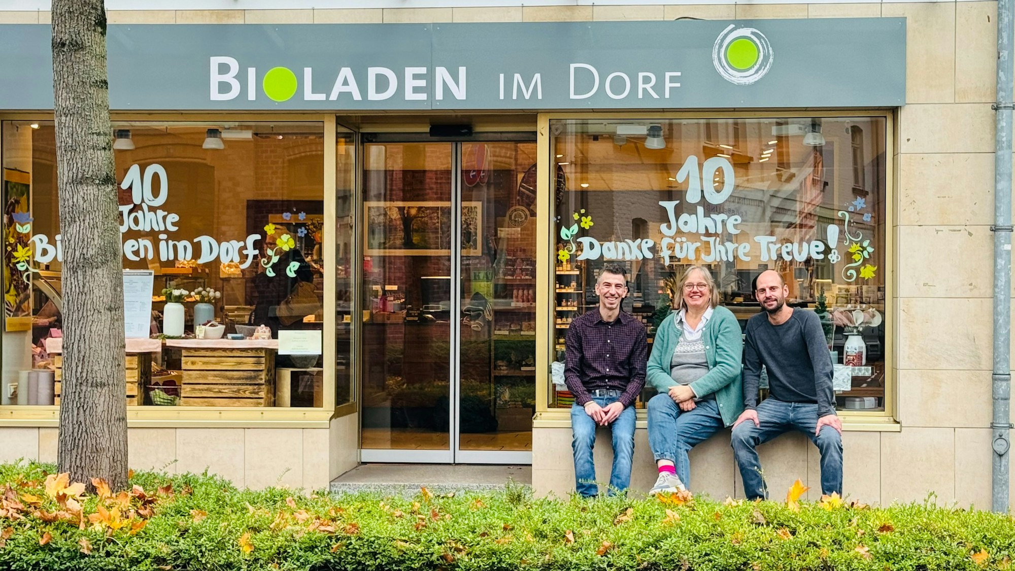Drei Menschen vor Bioladen