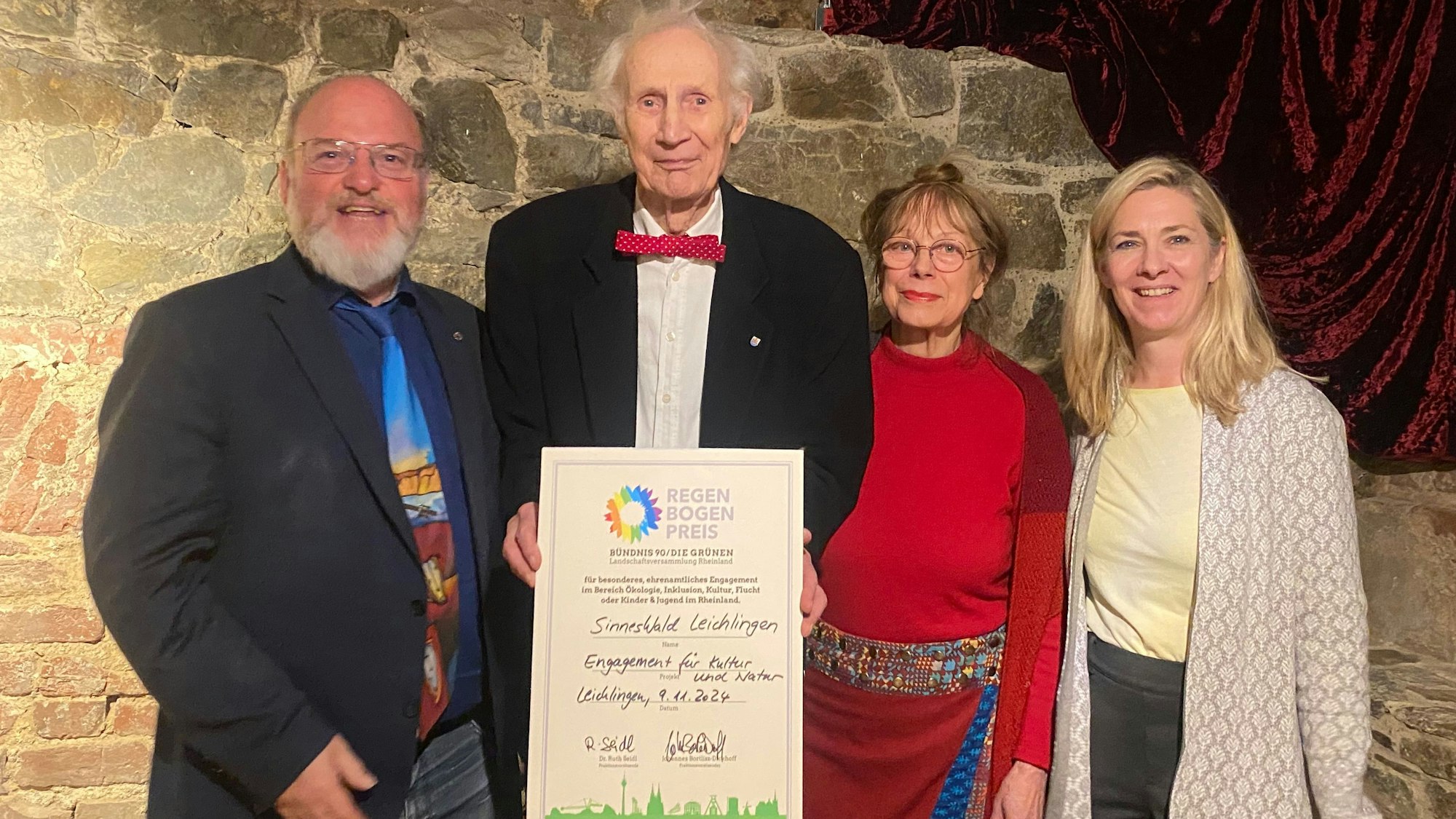 Zwei Männer und zwei Frauen halten eine Urkunde.