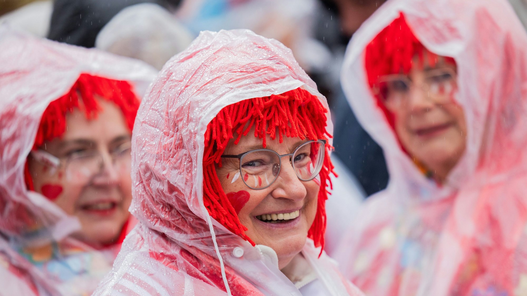Jecken mit Regenschutz feiern den Auftakt der Karnevalssession auf dem Heumarkt.
