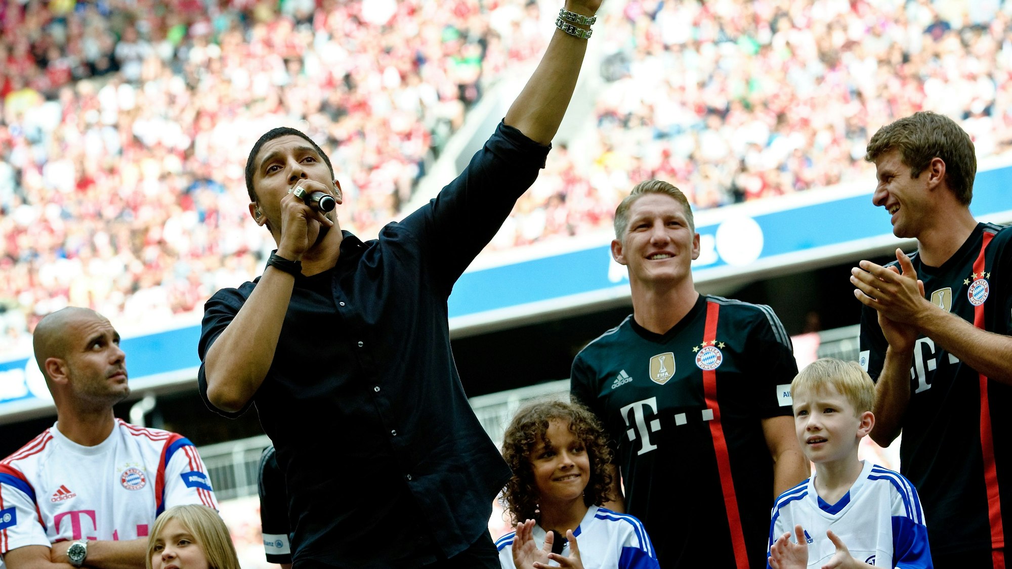 Andreas Bourani (vorne) trat im August 2014 bei der Teampräsentation des Fußball-Bundesligisten FC Bayern München in der Allianz Arena auf. Hinter ihm stehen Bayerns Trainer Pep Guardiola (l-r), Bastian Schweinsteiger und Thomas Müller.