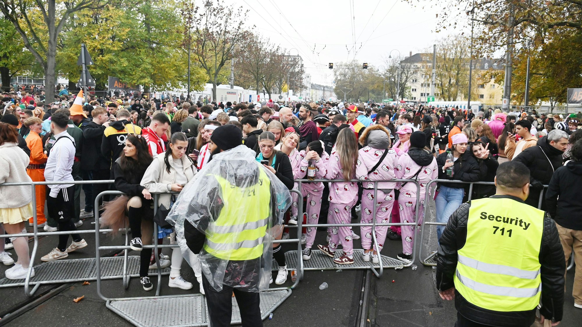Feiernde stehen vor einem Absperrgitter mit Sicherheitskräften.