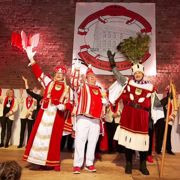 Ein männliches Dreigestirn steht winkend auf der Bühne der Turnhalle.