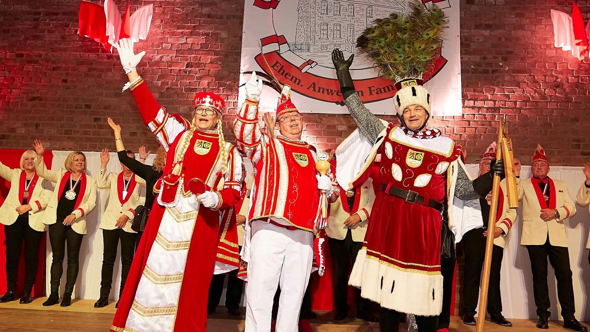 Ein männliches Dreigestirn steht winkend auf der Bühne der Turnhalle.