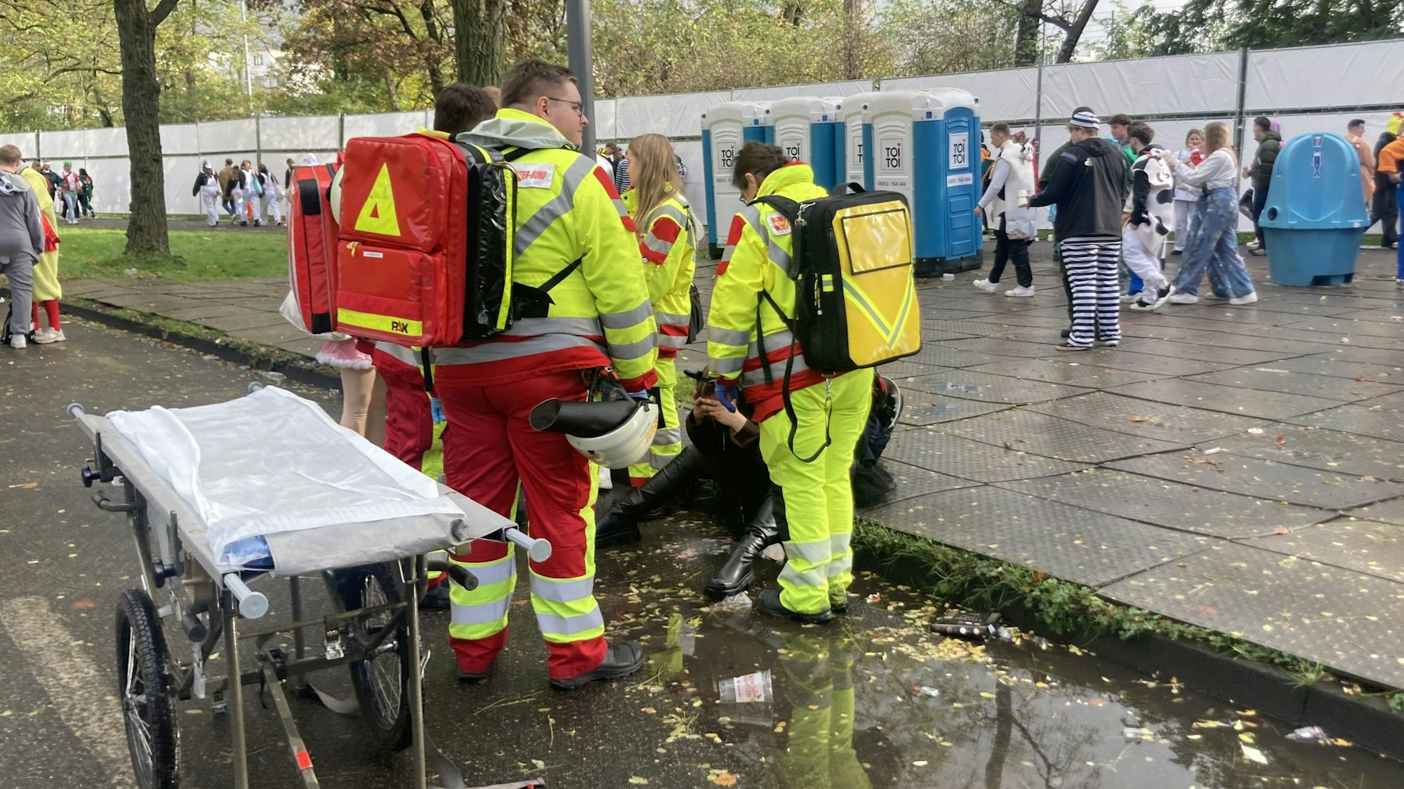 Das Foto zeigt eine Gruppe von Sanitätern rund um eine Person, die auf dem Bordstein sitzt.