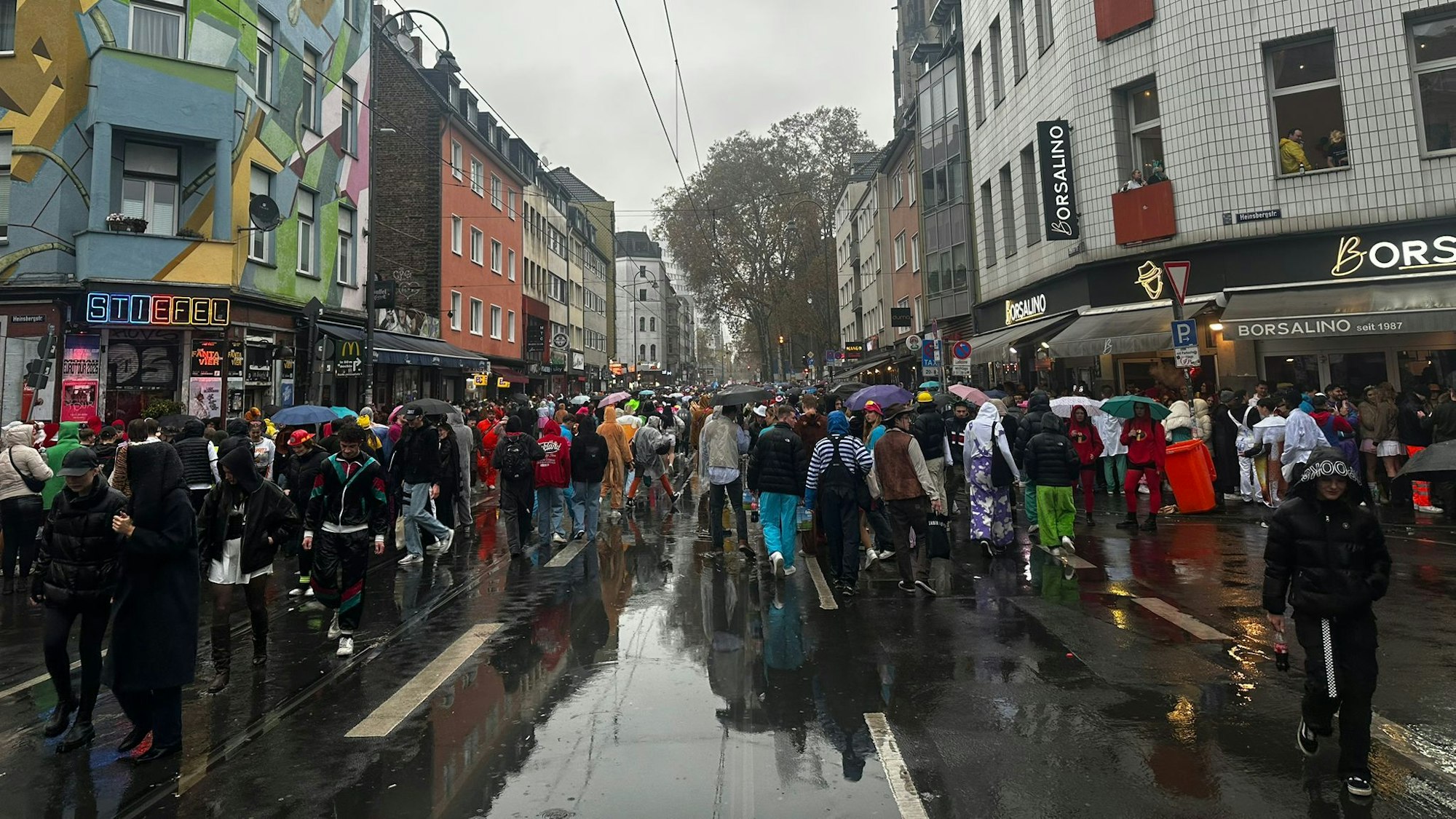 Auf der Zülpicher Straße sind viele Schirme wegen des Regens zu sehen.
