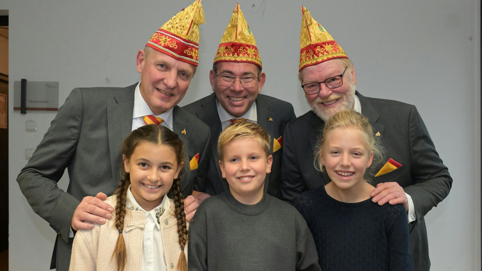 Jungfrau, Prinz und Bauer stehen hinter den beiden Mädchen und dem Jungen des Kinderdreigestirns.