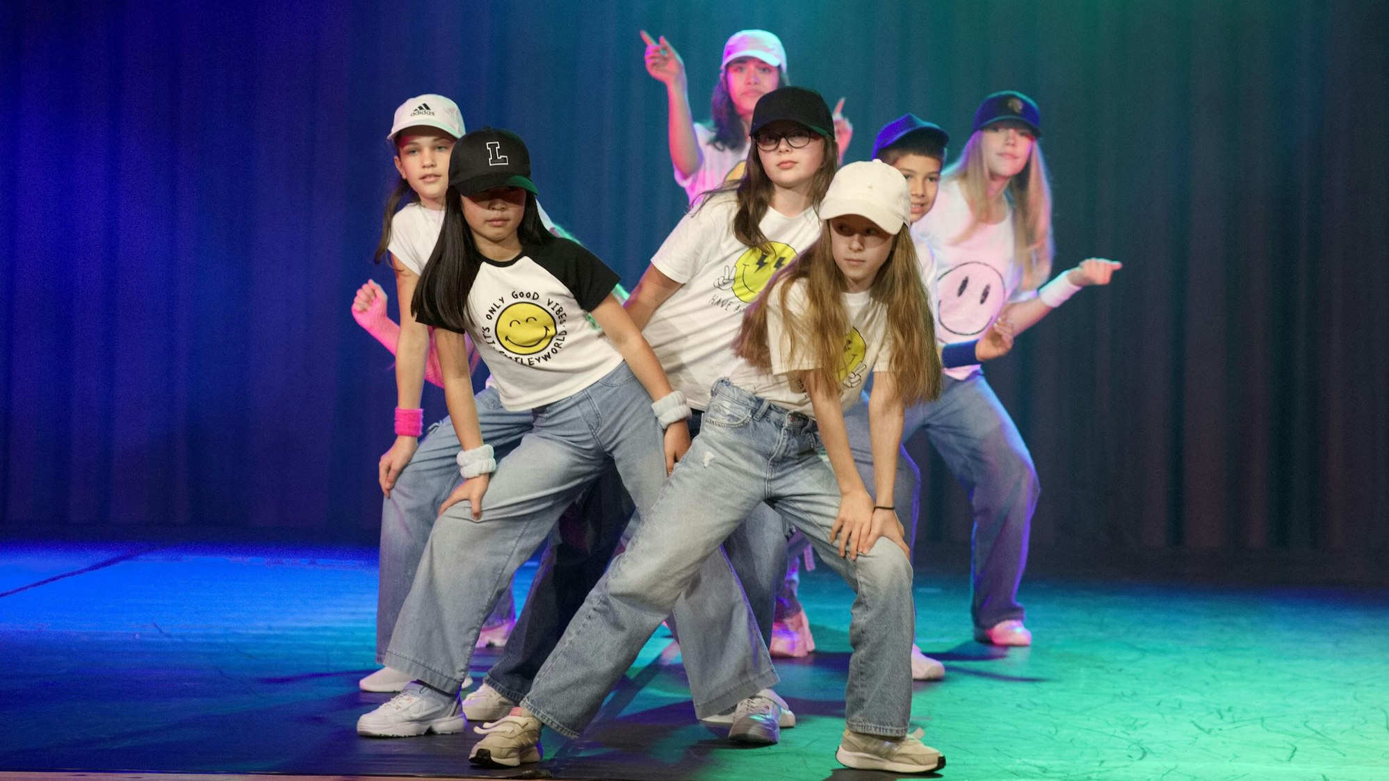 Mädchen mit Kappen haben sich auf einer Bühne aufgereiht und posieren.