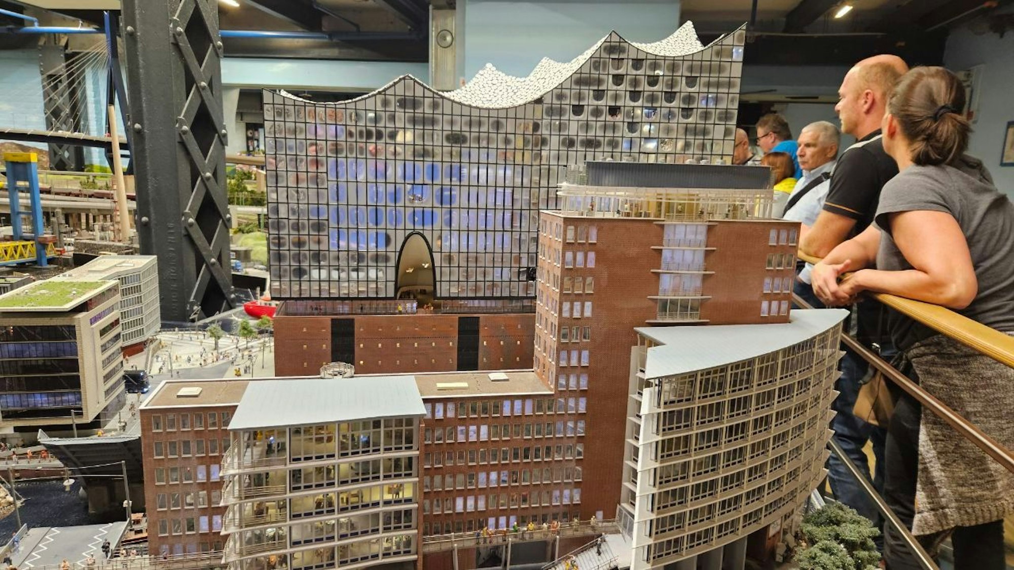 Im Miniaturwunderland in Hamburg wird auch die Elbphilharmonie in Klein aufgebaut. Menschen stehen an Geländern darum herum und schauen sich die Arbeiten an.