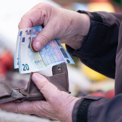 Eine Frau sortiert das Wechselgeld für ihre Einkäufe in ein Portemonnaie.