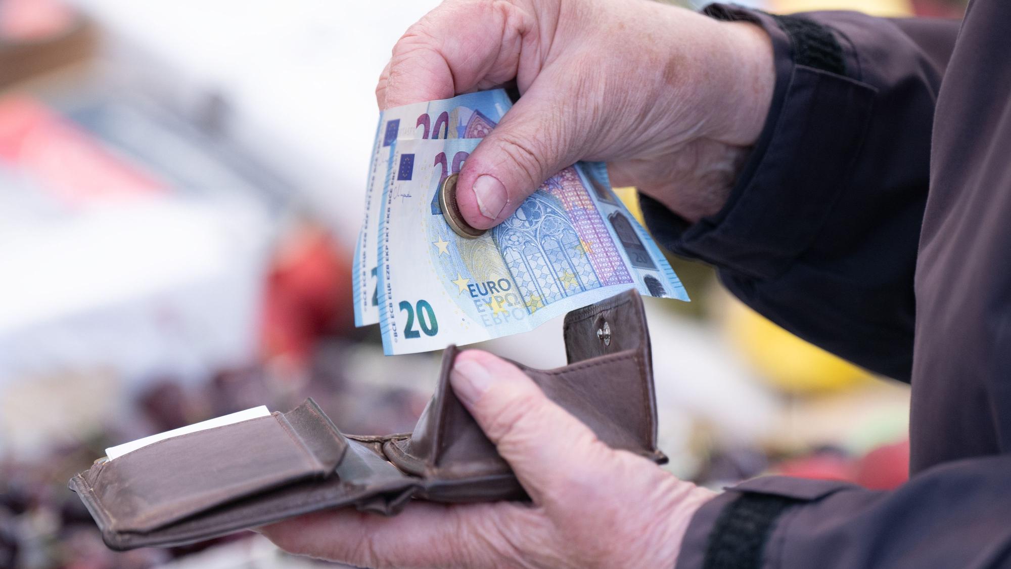 Eine Frau sortiert das Wechselgeld für ihre Einkäufe in ein Portemonnaie.