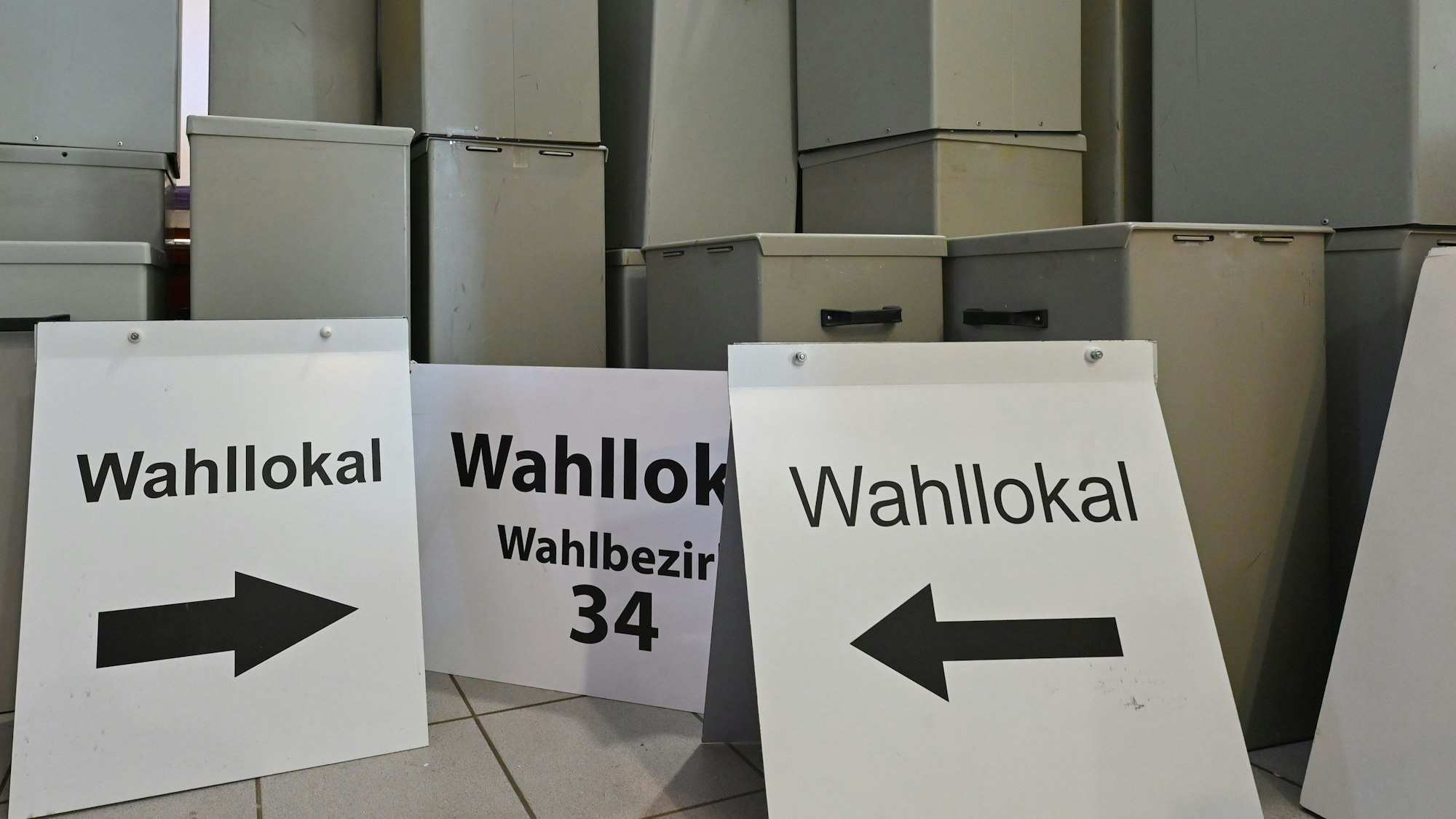 Wahlurnen und -schilder stehen in einem Lager. (Symbolbild)
