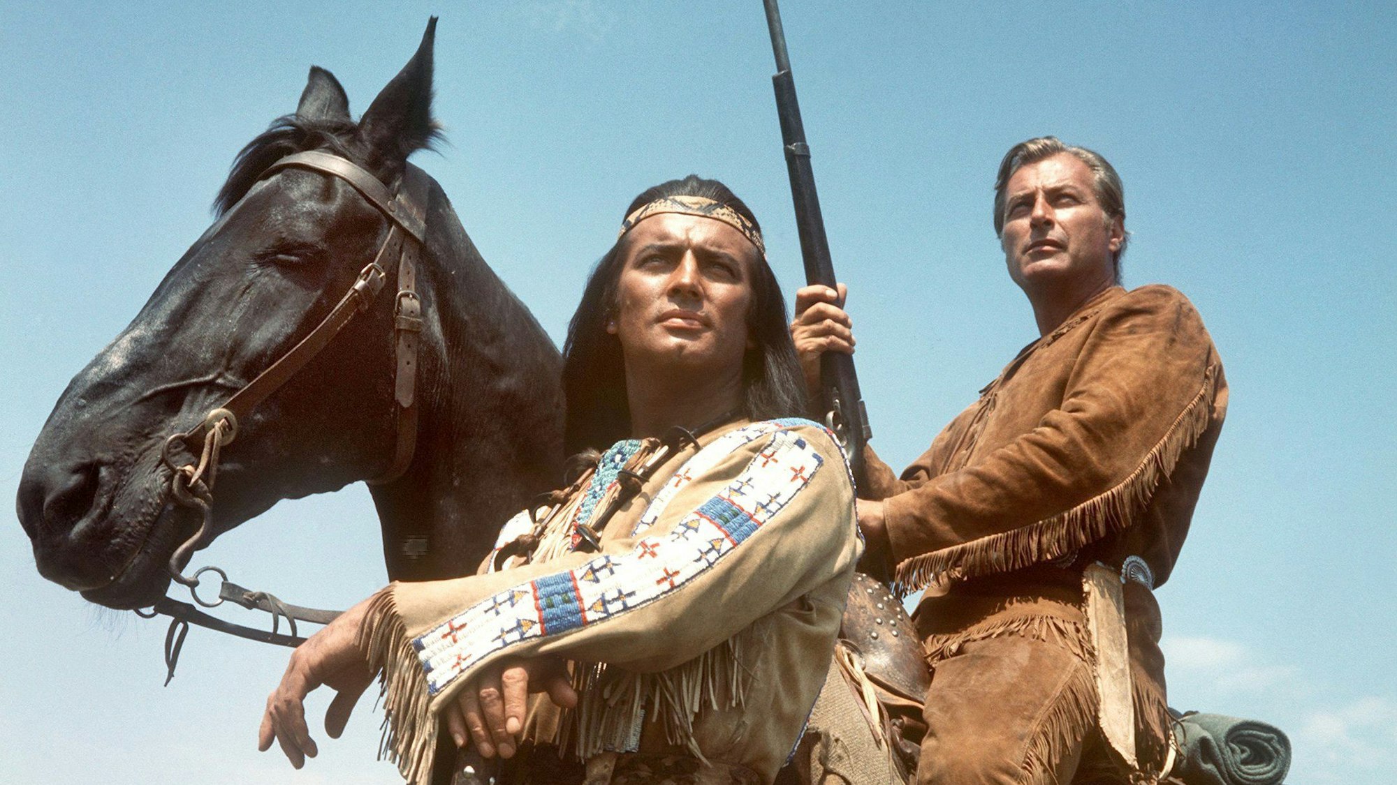 Das Foto zeigt den Schauspieler Pierre Brice (l) als Apachen-Häuptling Winnetou und Lex Barker als seinen Blutsbruder Old Shatterhand in einer Szene der Karl-May-Verfilmung „Im Tal des Todes“.