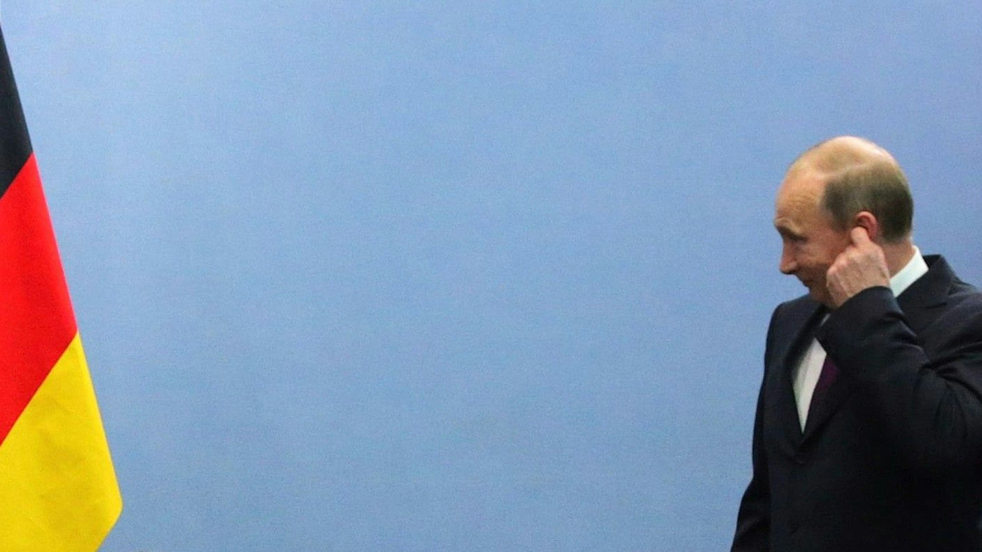 Kremlchef Wladimir Putin neben einer deutschen Fahne. Der russische Präsident schweigt bislang zum Wahlsieg von Friedrich Merz in Deutschland. (Archivbild)