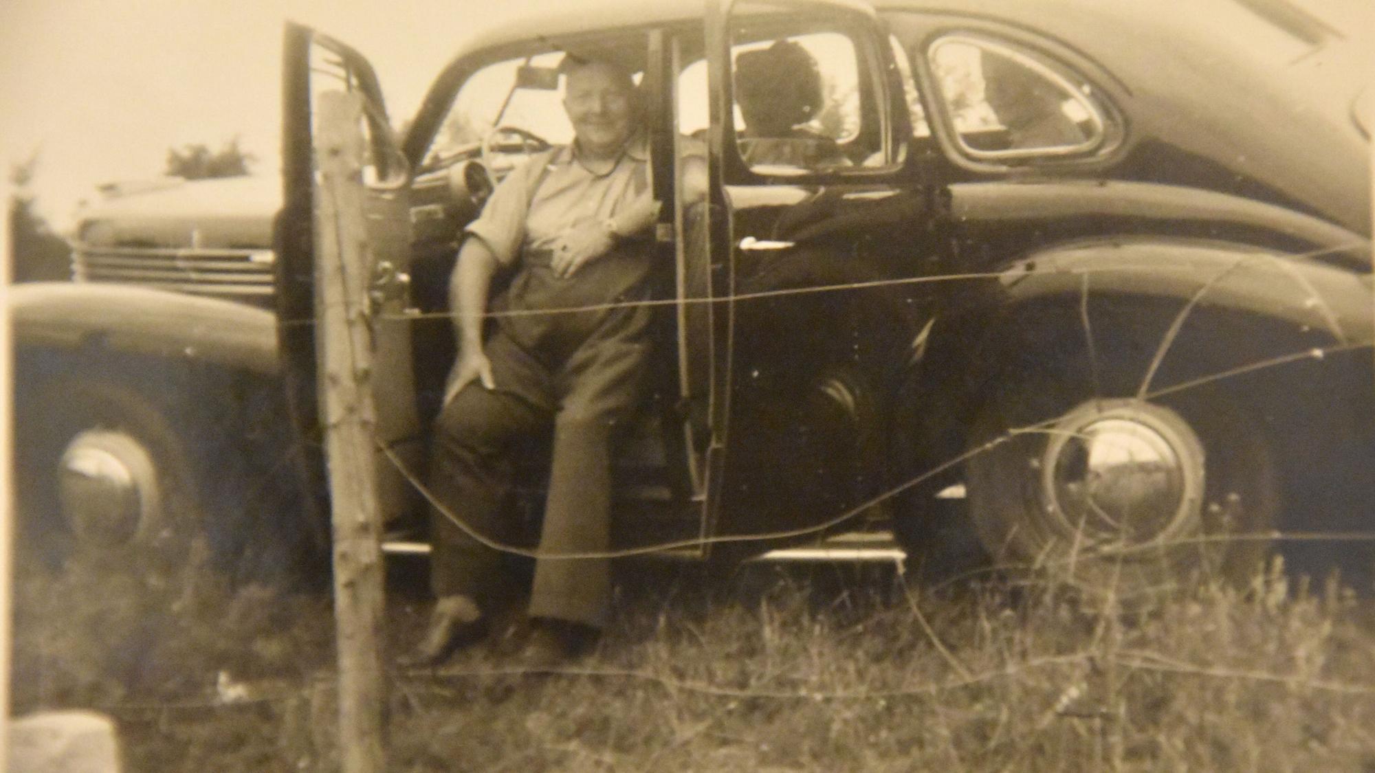 Das alte Foto zeigt einen Mann in einem Auto.