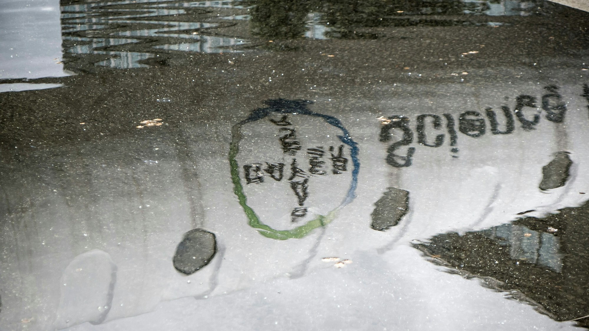 Die Bayer-Werbung an der Röhre über der B8 spiegelt sich in einer Pfütze.