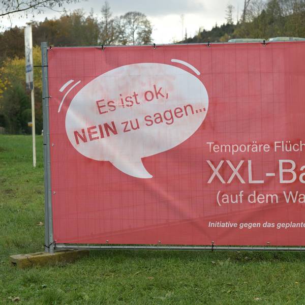 Ein rotes Protestplakat gegen den Bau einer Flüchtlingsunterkunft.
