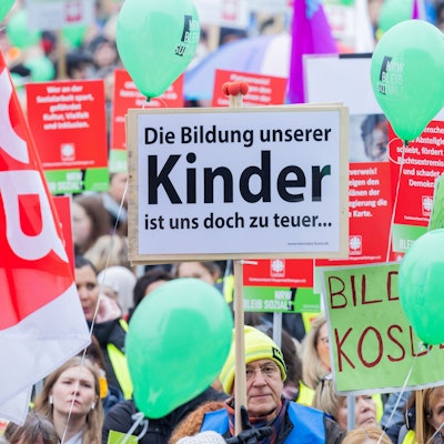 Ein Mann hält ein Plakat mit der Aufschrift "Die Bildung unserer Kinder ist uns doch zu teuer..." bei einer Kundgebung von Wohlfahrtverbänden gegen geplante Kürzungen der Landesregierung auf den Oberkasseler Rheinwiesen.