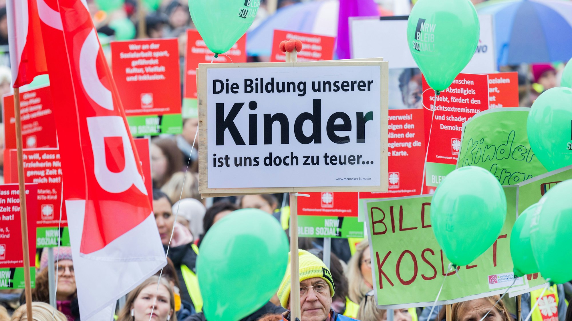 Ein Mann hält ein Plakat mit der Aufschrift "Die Bildung unserer Kinder ist uns doch zu teuer..." bei einer Kundgebung von Wohlfahrtverbänden gegen geplante Kürzungen der Landesregierung auf den Oberkasseler Rheinwiesen.