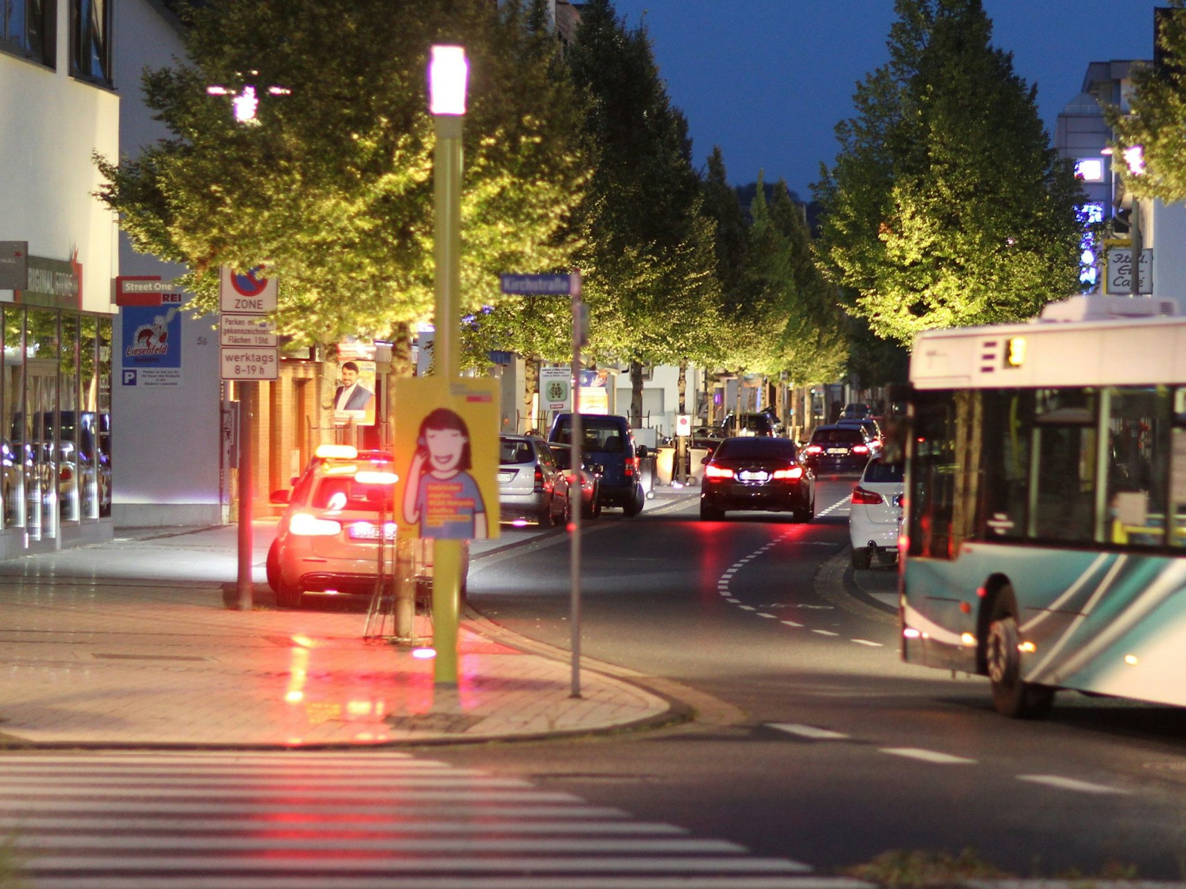 Eine Straße mit Autos, Bussen und breiten Bürgersteigen