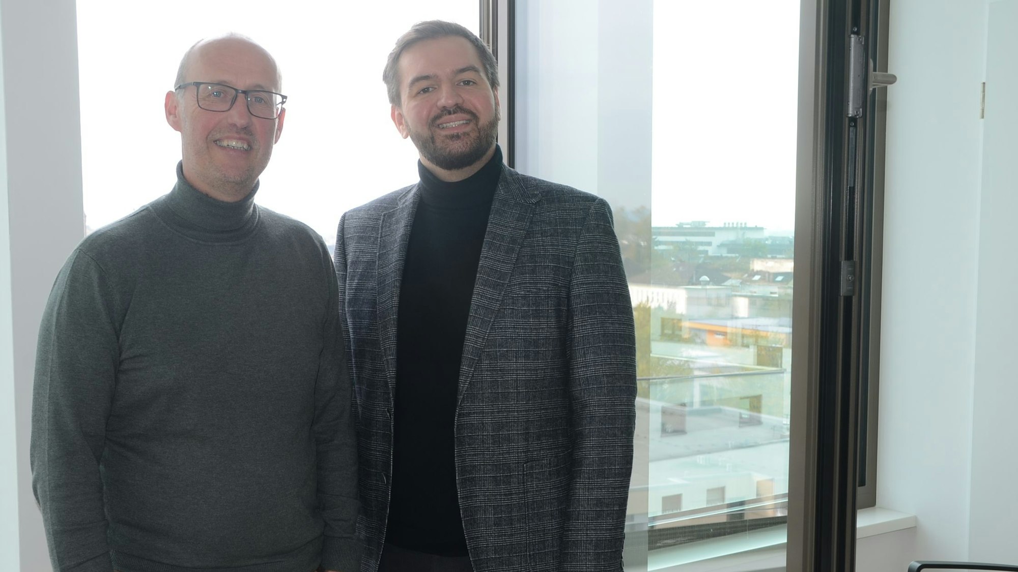 Zwei Männer stehen vor einem Fenster..